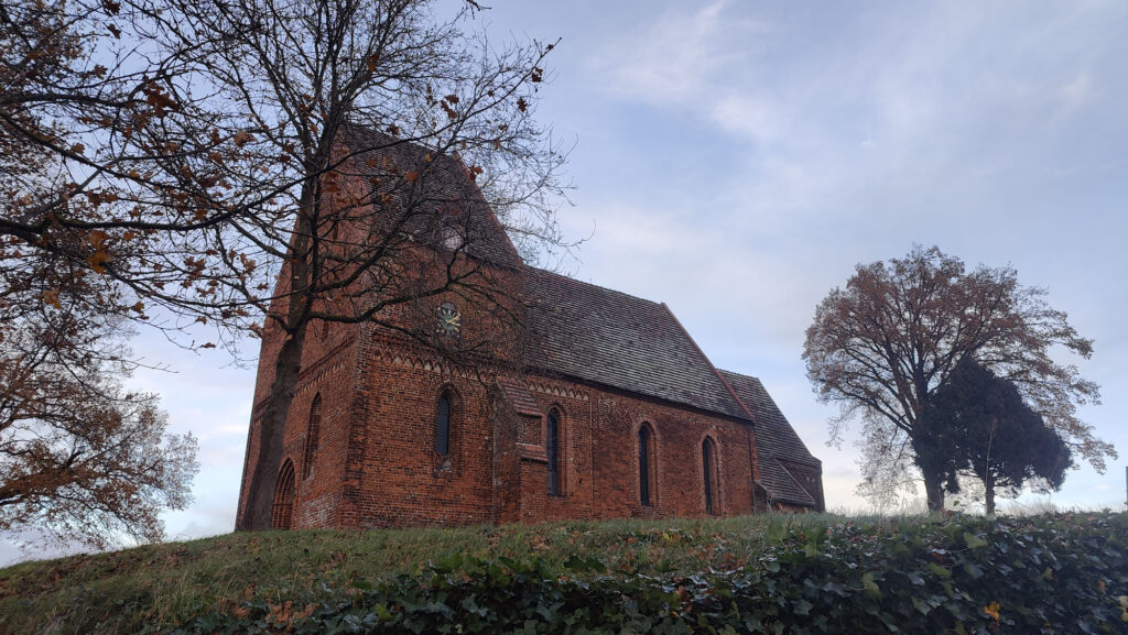 Die Kirche St. Johannes in Kirch Mummendorf auf dem Hügel von Südwesten aus fotografiert. Es ist Herbst, die Bäume haben keine Blätter.